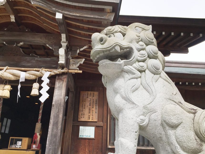古賀神社を背景に撮影した阿形（あぎょう）の口を開けた狛犬