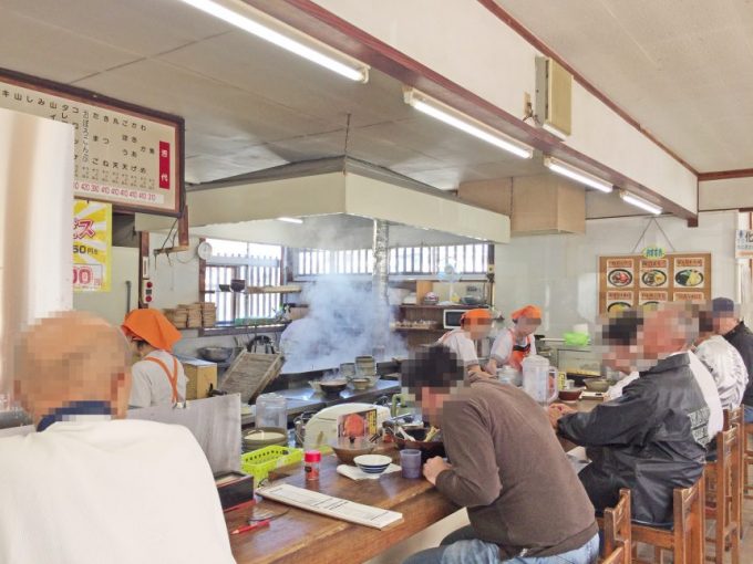 牧のうどんのカウンターでうどんをすするお客さん