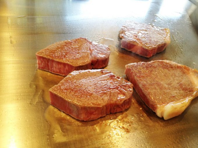 鉄板の上で焼かれるお肉。脂身の部分を切り落とされ鋭角な断面が食欲をそそる。